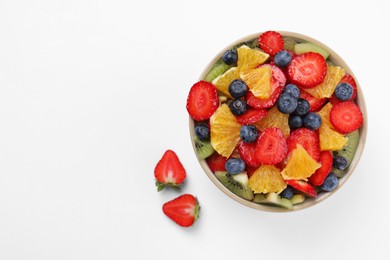 Photo of Yummy fruit salad in bowl on white background, top view. Space for text