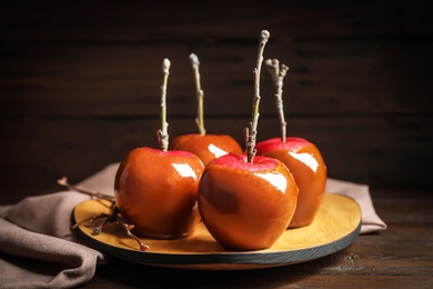 Photo of Plate with delicious caramel apples on wooden table