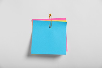 Photo of Paper notes attached with safety pin to white background, top view