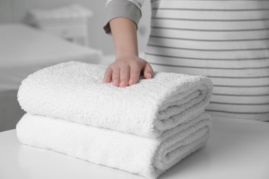 Photo of Woman touching soft white towel indoors, closeup