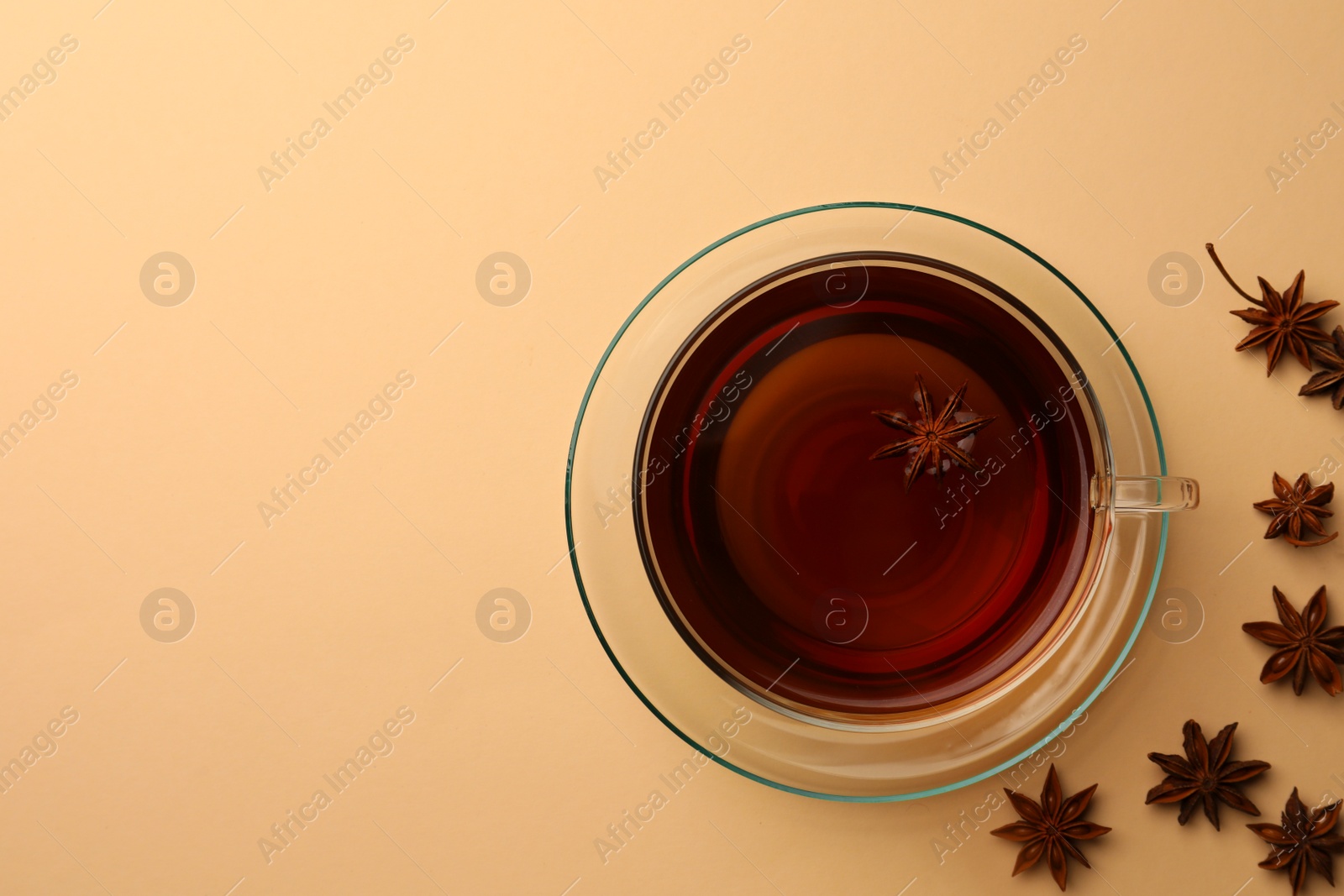 Photo of Cup of tea and anise stars on beige background, flat lay. Space for text