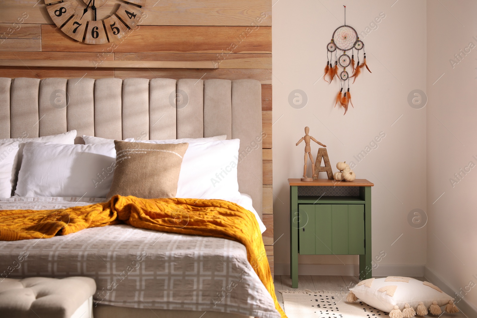 Photo of Beautiful dream catcher hanging near bed in stylish room interior