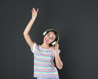 Beautiful young woman listening to music with headphones on black background