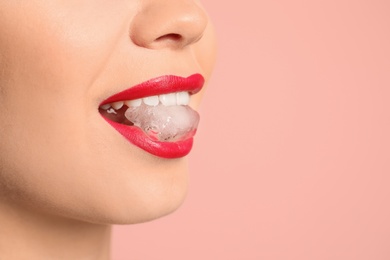 Young woman holding ice cube in mouth on color background, closeup. Space for text