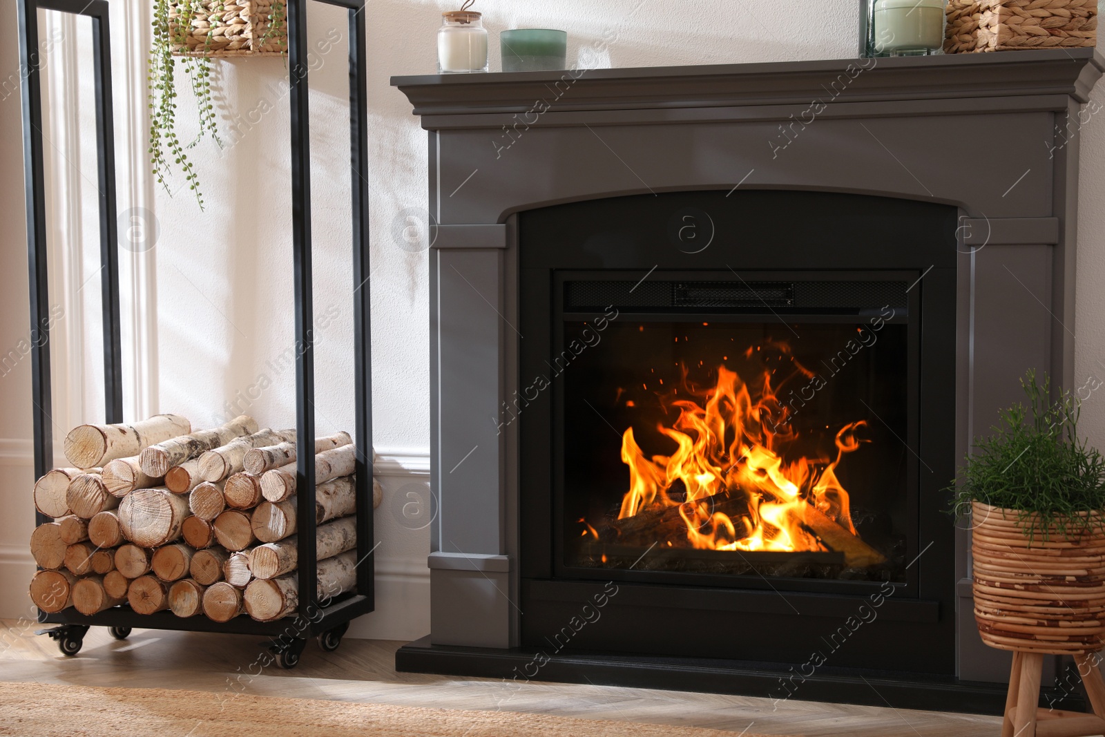 Photo of Electric fireplace, rack with wood and beautiful decor elements indoors. Interior design