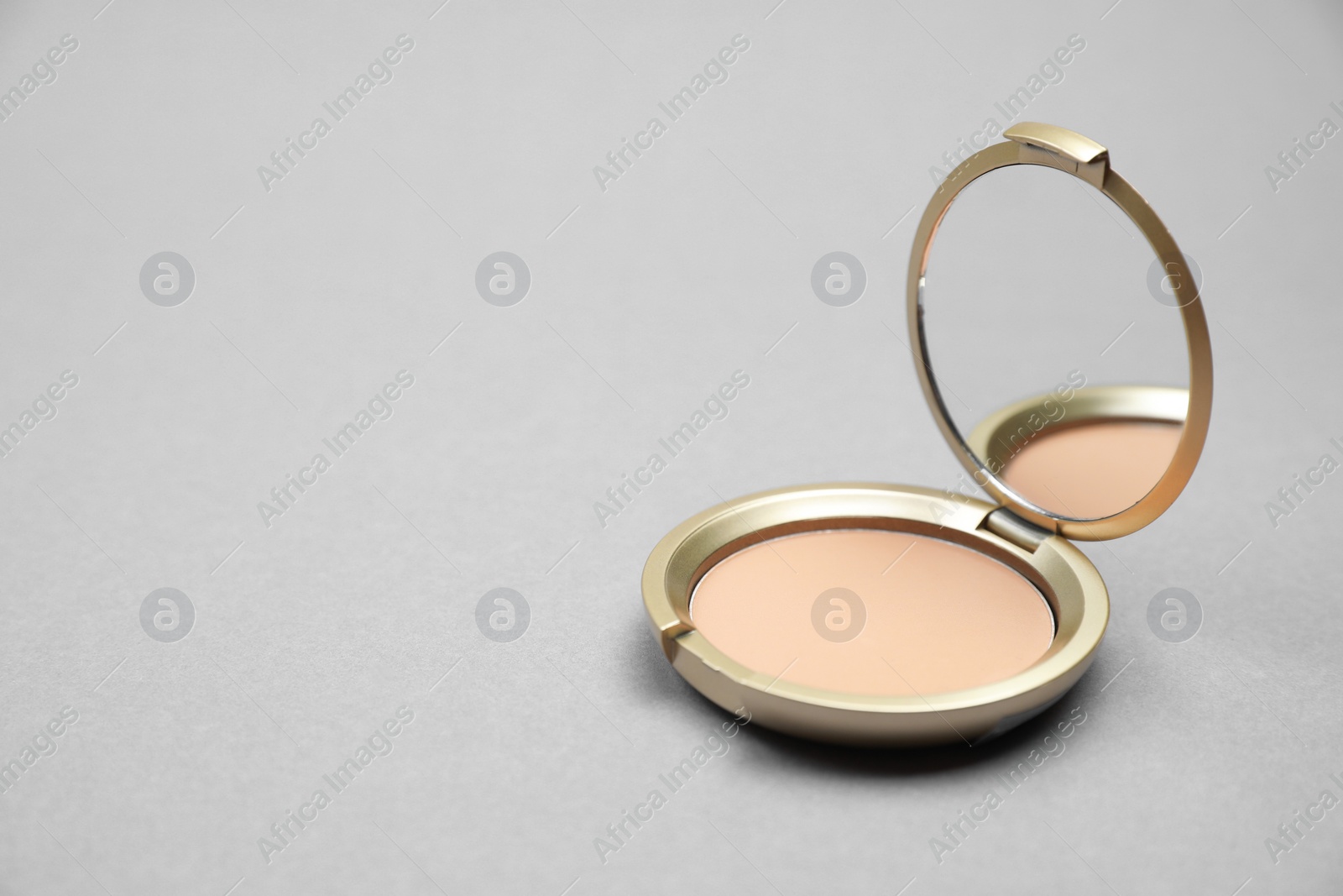 Photo of Open face powder with mirror on light grey background. Space for text