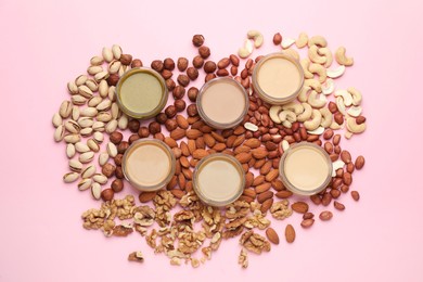 Different types of delicious nut butters and ingredients on pink background, flat lay