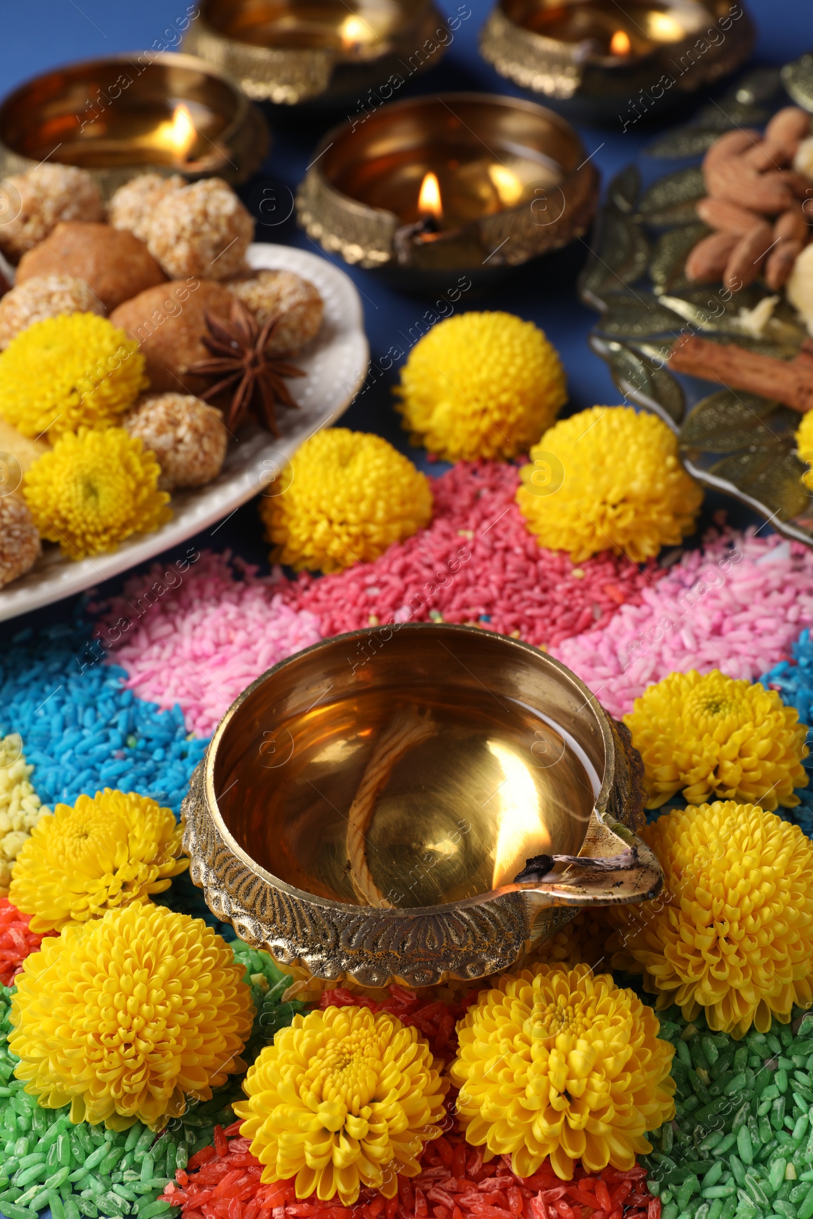 Photo of Diwali celebration. Tasty Indian sweets, colorful rangoli and diya lamps on table, closeup