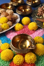 Photo of Diwali celebration. Tasty Indian sweets, colorful rangoli and diya lamps on table, closeup