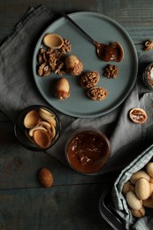 Photo of Freshly baked homemade walnut shaped cookies and boiled condensed milk on wooden table, flat lay