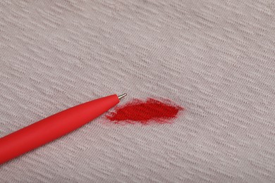 Photo of Pen and stain of red ink on beige shirt. Space for text