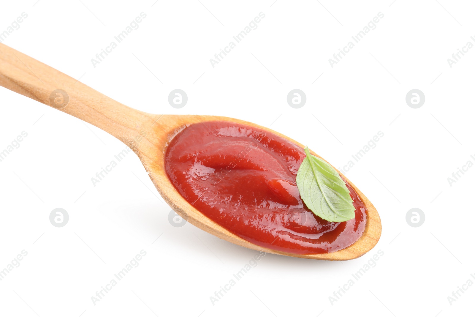 Photo of Wooden spoon with tasty ketchup and basil isolated on white