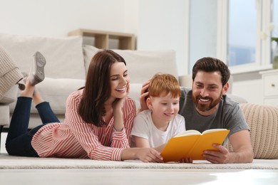 Photo of Happy parents with their child reading book on floor at home