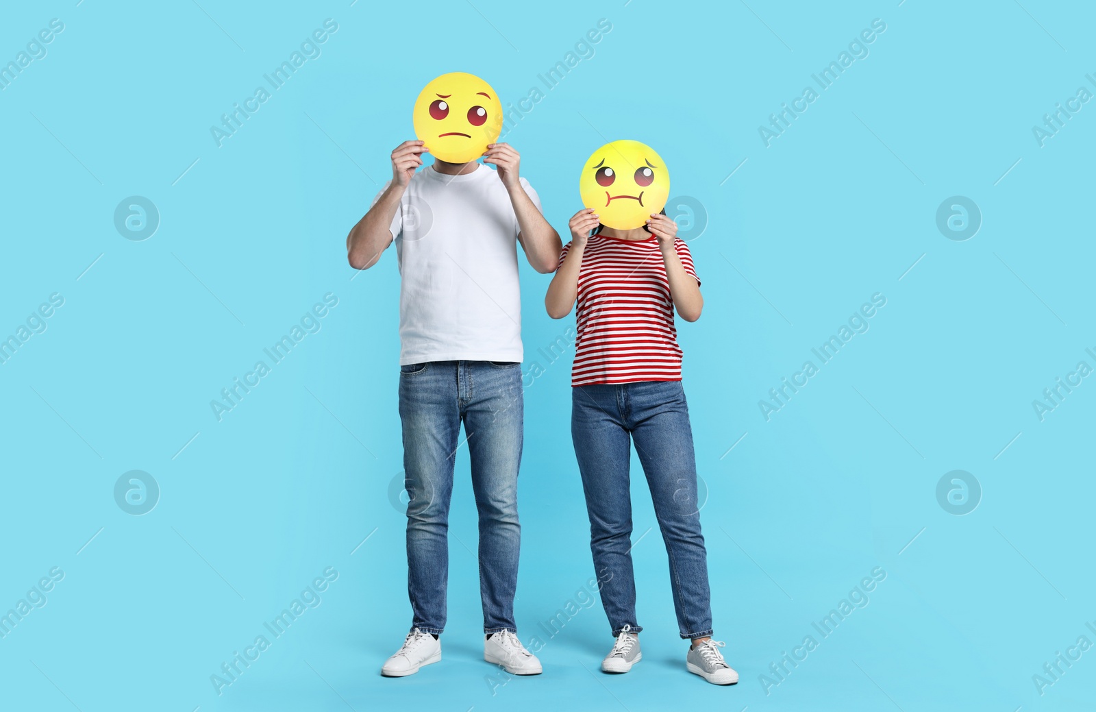 Photo of People covering faces with emoticons on light blue background