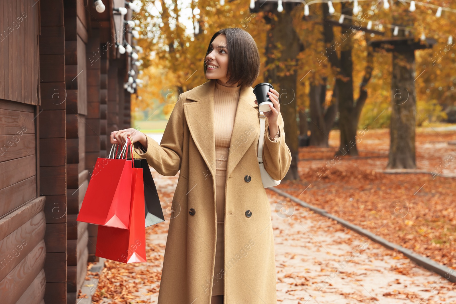 Photo of Special Promotion. Happy young woman with shopping bags and cup of drink on city street