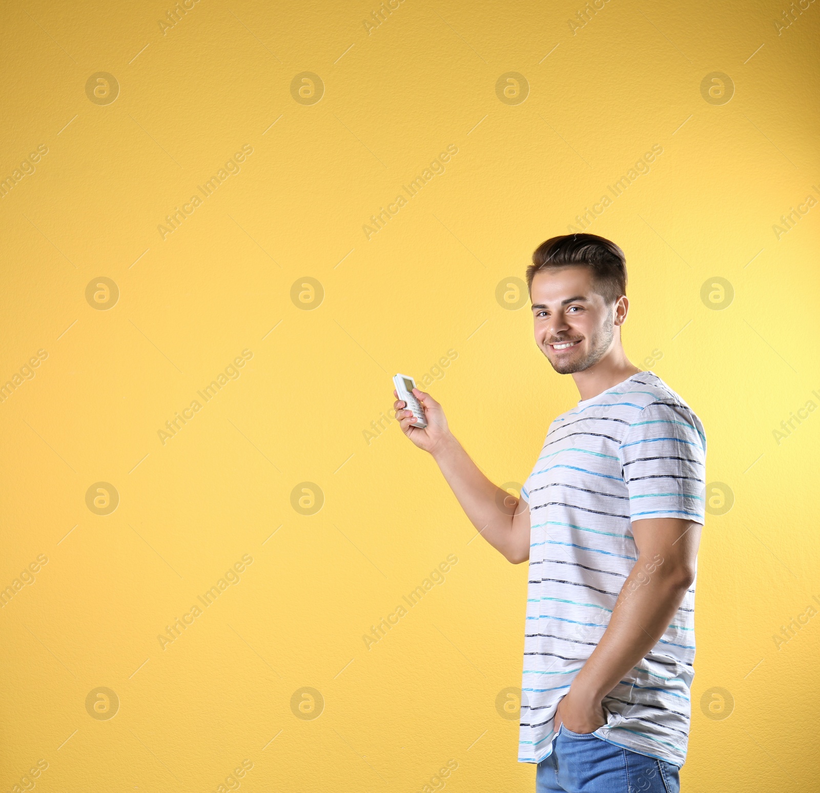 Photo of Young man with air conditioner remote on color background