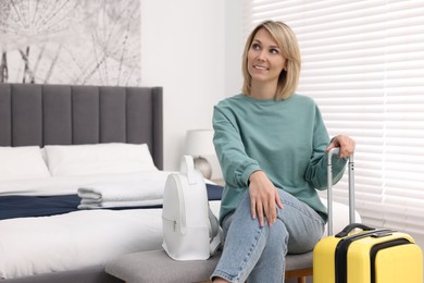Smiling guest with backpack and suitcase in stylish hotel room