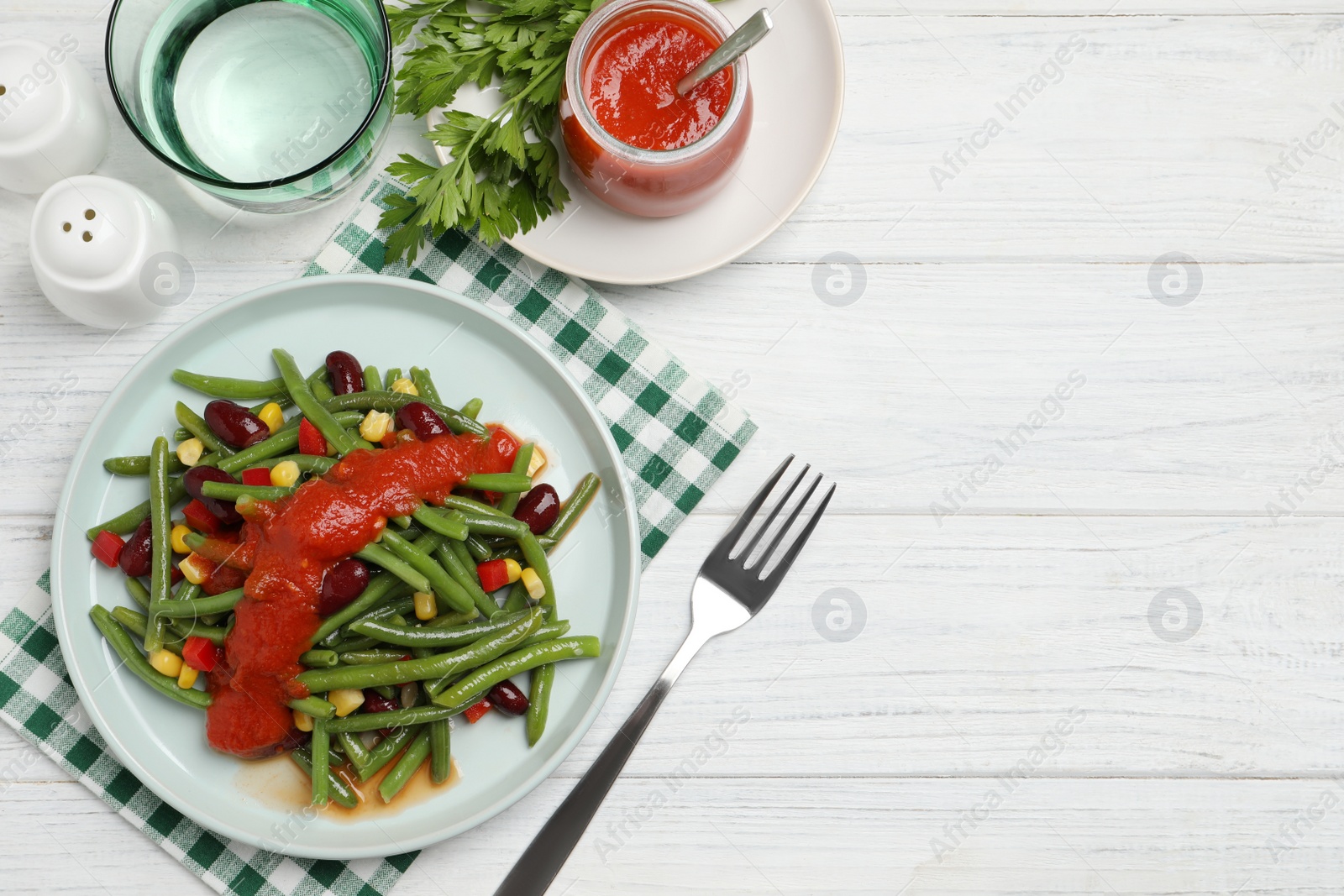 Photo of Delicious salad with green beans and tomato sauce served on white wooden table, flat lay. Space for text