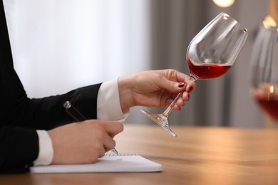Photo of Sommelier tasting wine at table indoors, closeup
