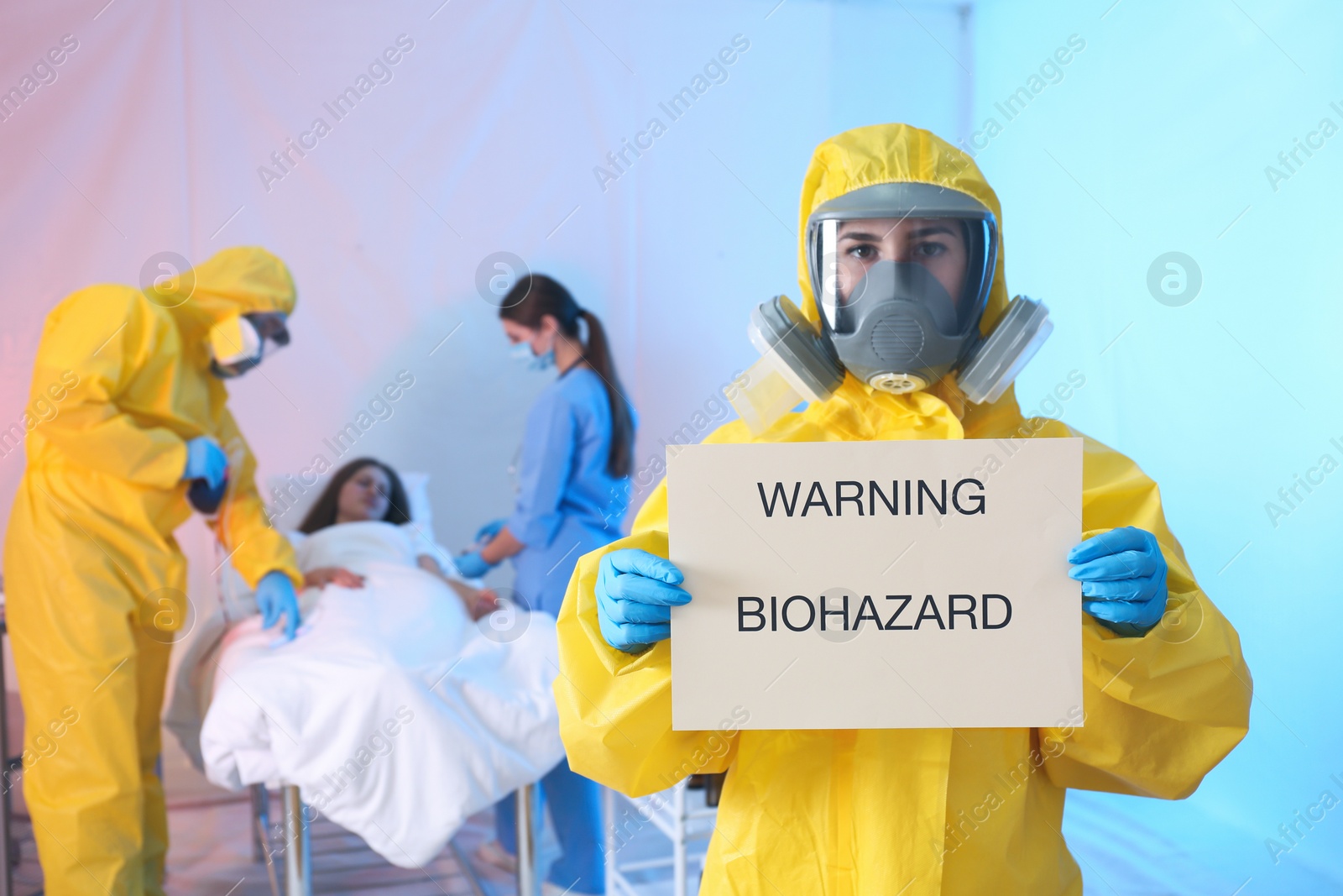 Photo of Paramedic holding sign with words WARNING BIOHAZARD in quarantine ward. Virus awareness