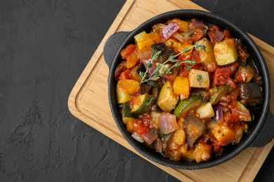 Photo of Dish with tasty ratatouille on black table, top view. Space for text