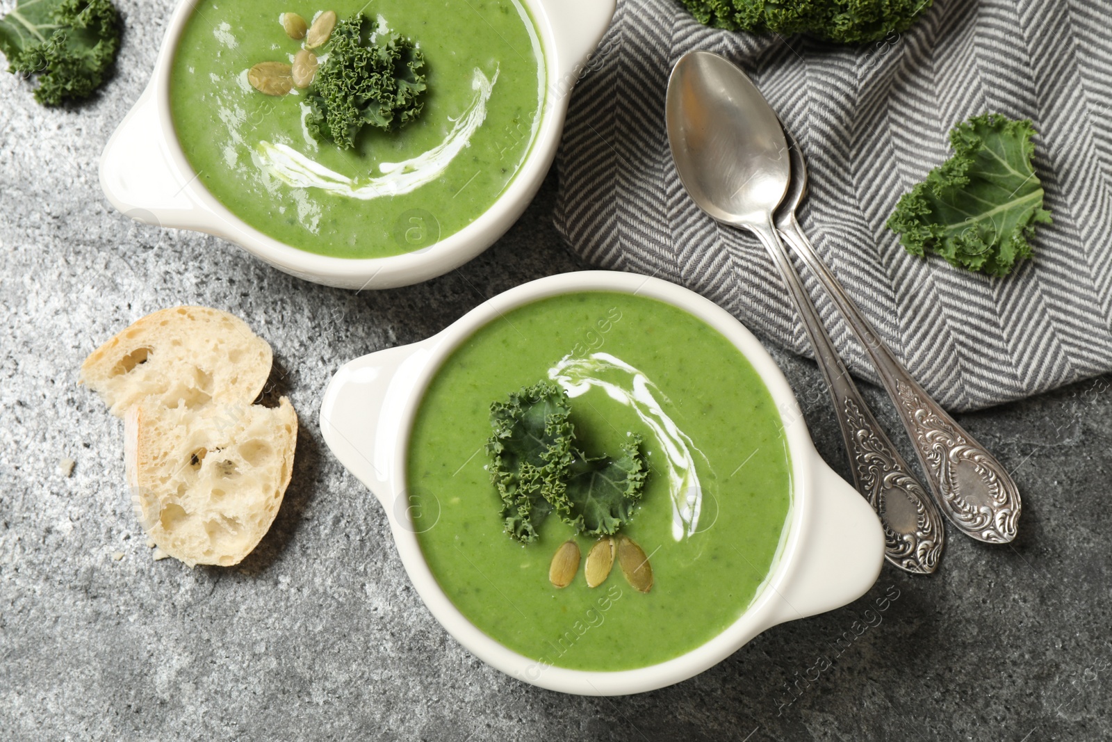 Photo of Tasty kale soup served on grey table, flat lay