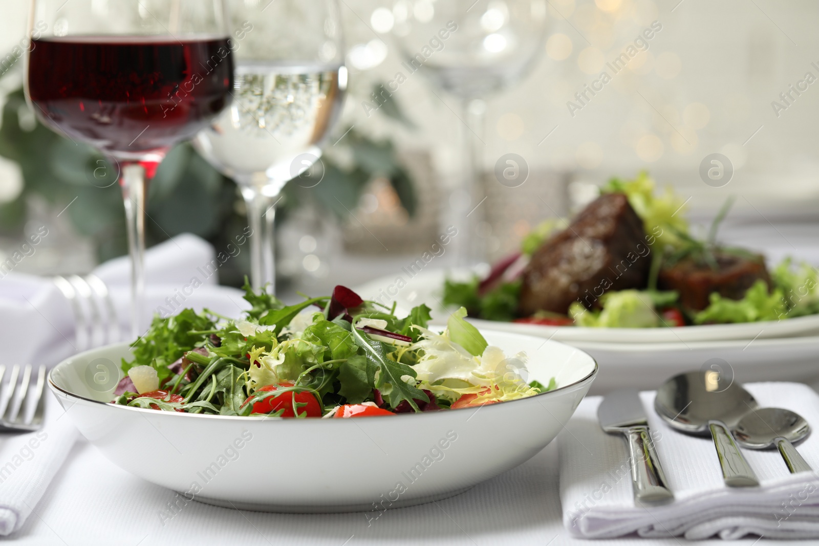 Photo of Delicious salad and wine served on table in restaurant