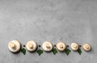 Photo of Flat lay composition with fresh champignon mushrooms on grey background, space for text