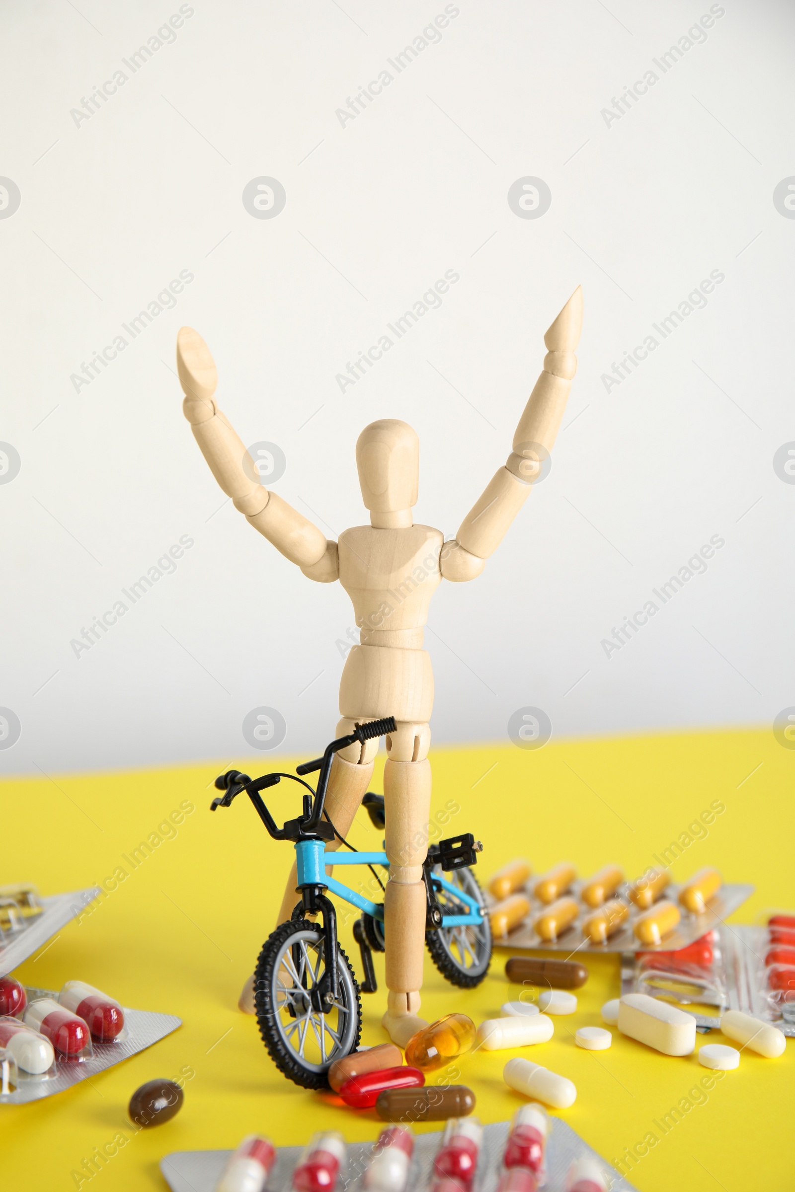 Photo of Pills, sportsman and bike model on yellow table. Using doping in cycling sport concept