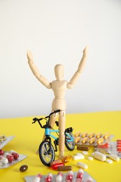 Pills, sportsman and bike model on yellow table. Using doping in cycling sport concept