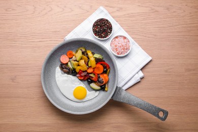 Photo of Frying pan with tasty cooked egg and vegetables on wooden table, top view