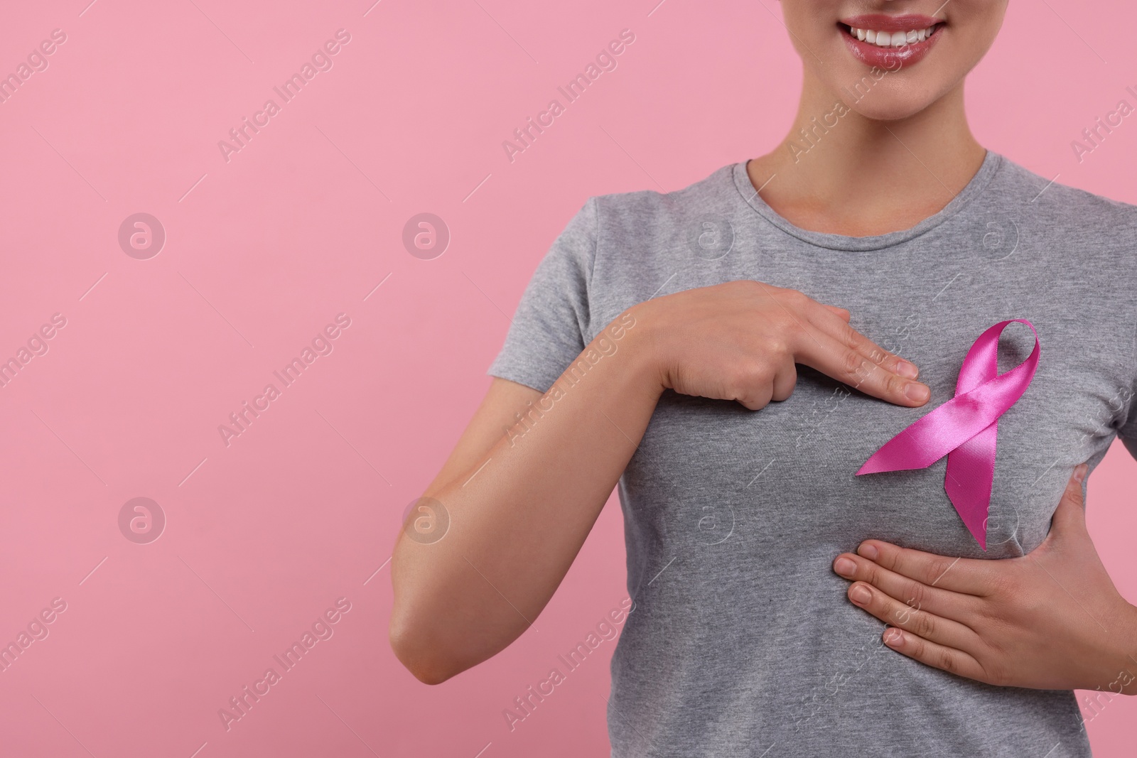 Photo of Woman with pink ribbon on color background, closeup and space for text. Breast cancer awareness