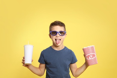 Photo of Boy with 3D glasses, popcorn and beverage during cinema show on color background