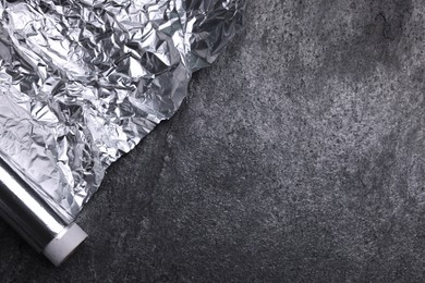 Photo of Roll of aluminum foil on grey table, top view. Space for text