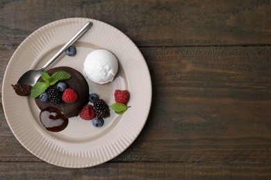 Delicious chocolate fondant served with fresh berries and ice cream on wooden table, top view. Space for text