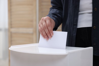 Photo of Woman putting her vote into ballot box on blurred background, closeup