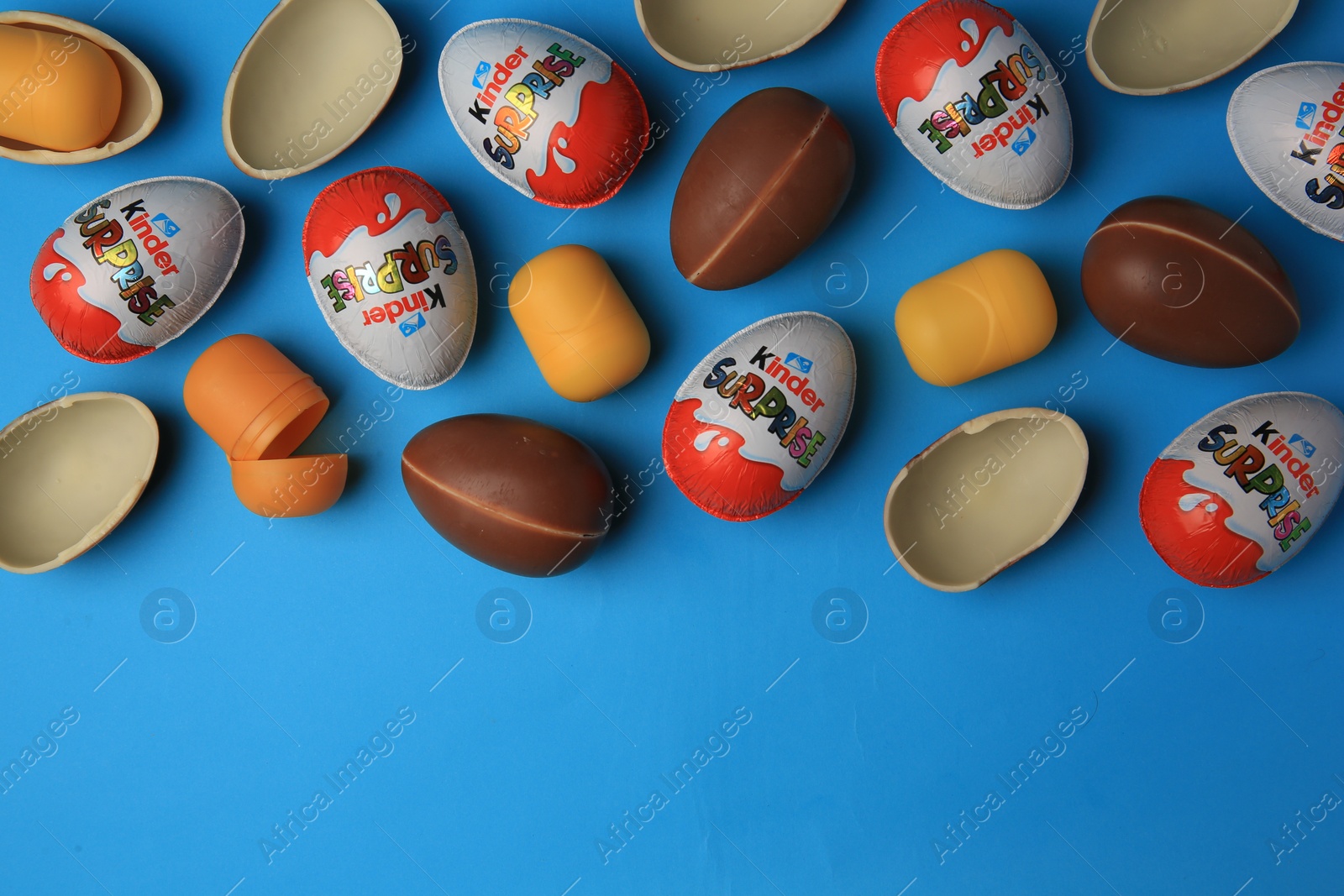 Photo of Sveti Vlas, Bulgaria - June 29, 2023: Kinder Surprise Eggs and plastic capsules on light blue background, flat lay. Space for text