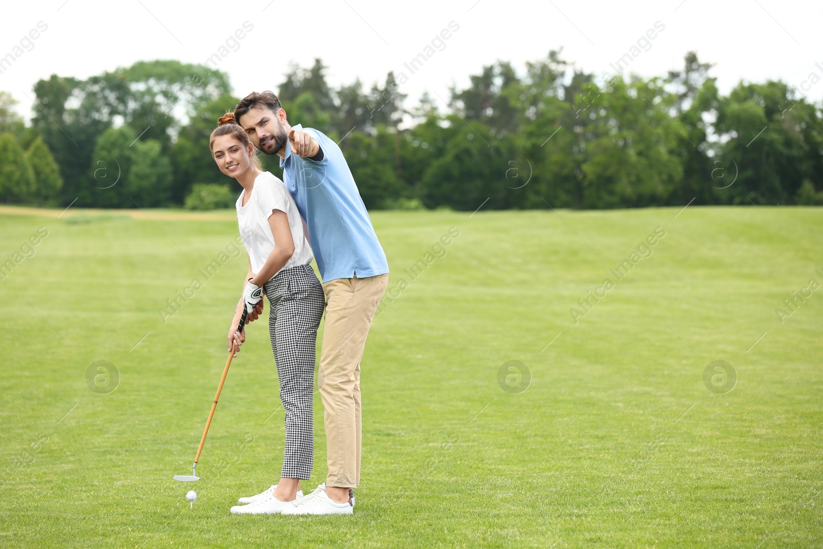 Photo of Coach teaching woman to play golf on green course