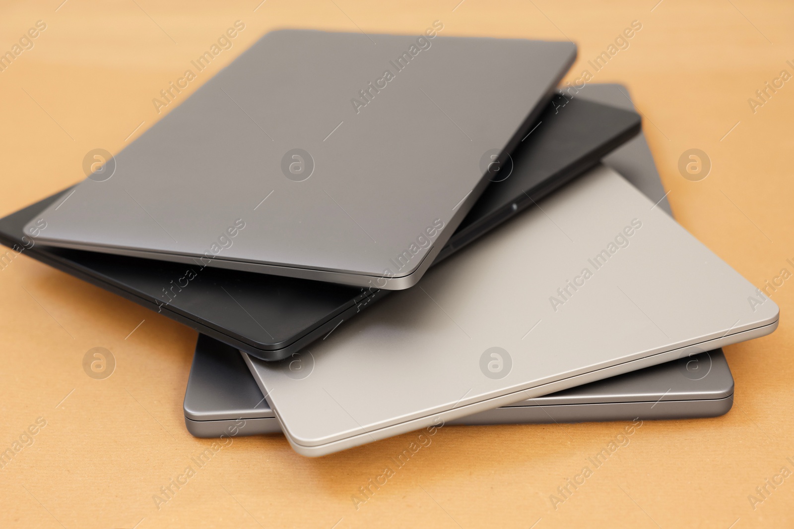 Photo of Different modern laptops on brown background, closeup