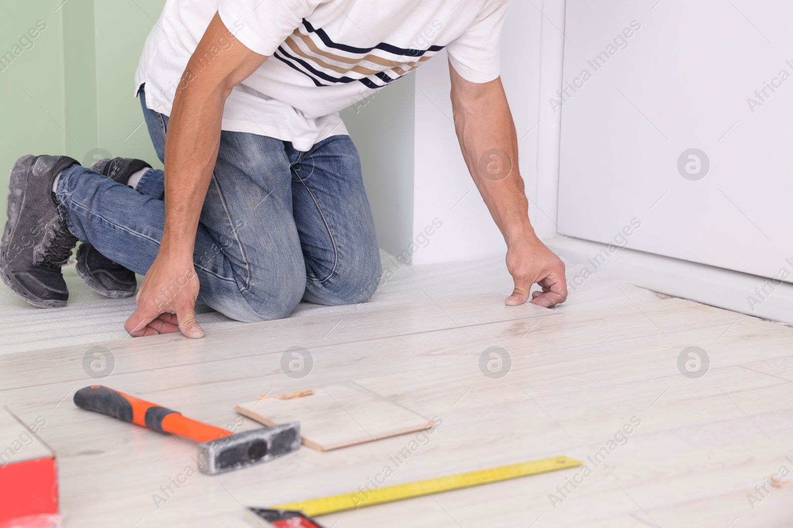 Photo of Man installing new laminate flooring indoors, closeup