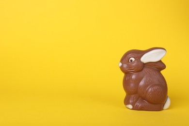 Photo of Chocolate bunny on yellow background, space for text. Easter celebration