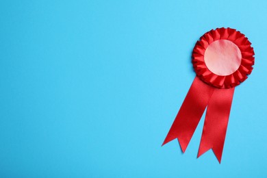 Photo of Red award ribbon on turquoise background, top view. Space for text