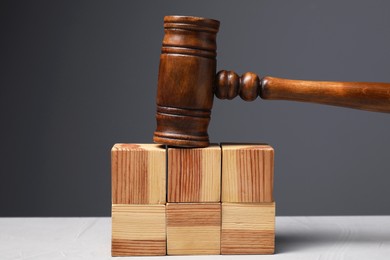 Photo of Law. Blank wooden cubes and gavel on light table against gray background