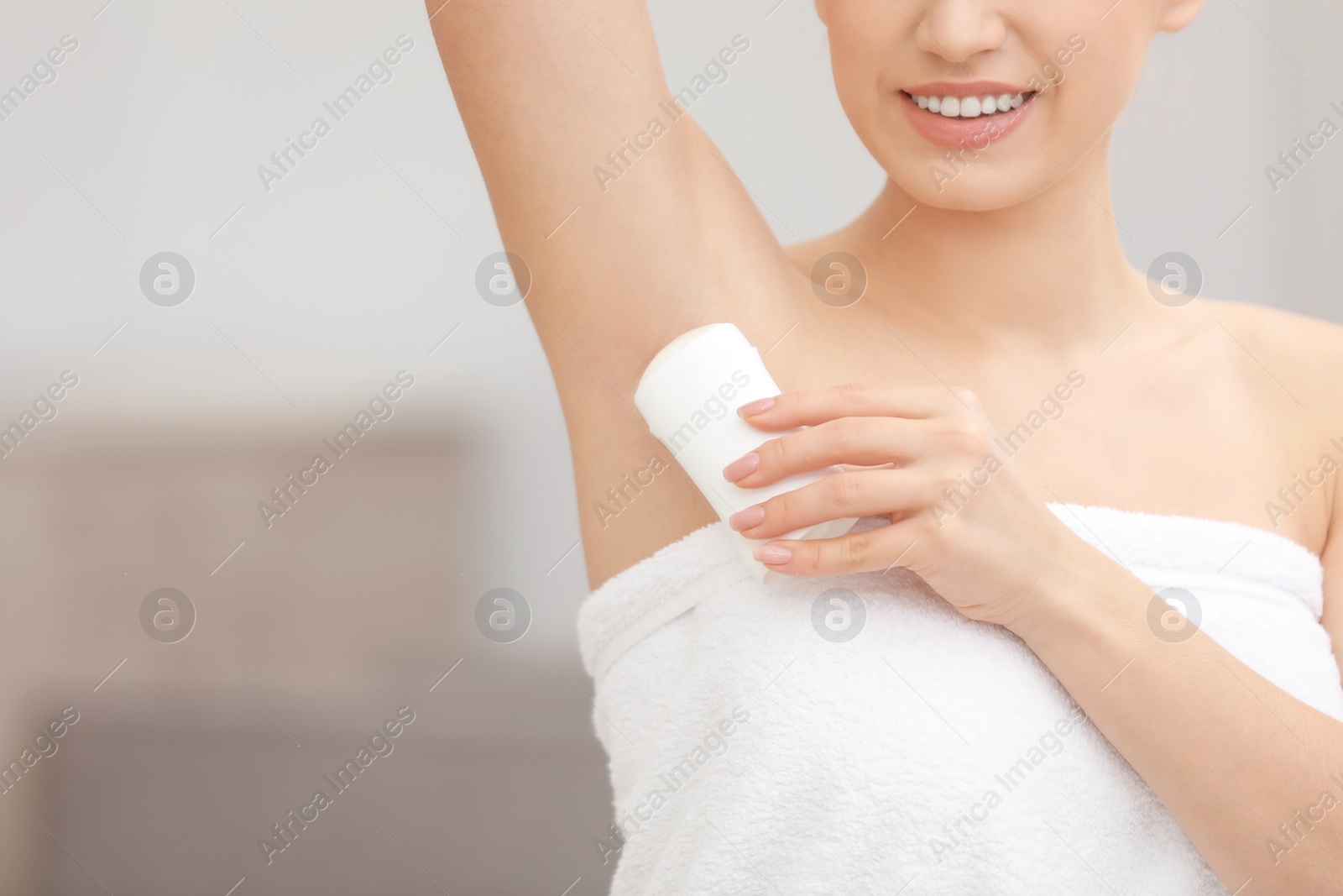 Photo of Beautiful young woman applying deodorant after shower on blurred background