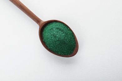 Photo of Spoon with spirulina algae powder on white background, top view