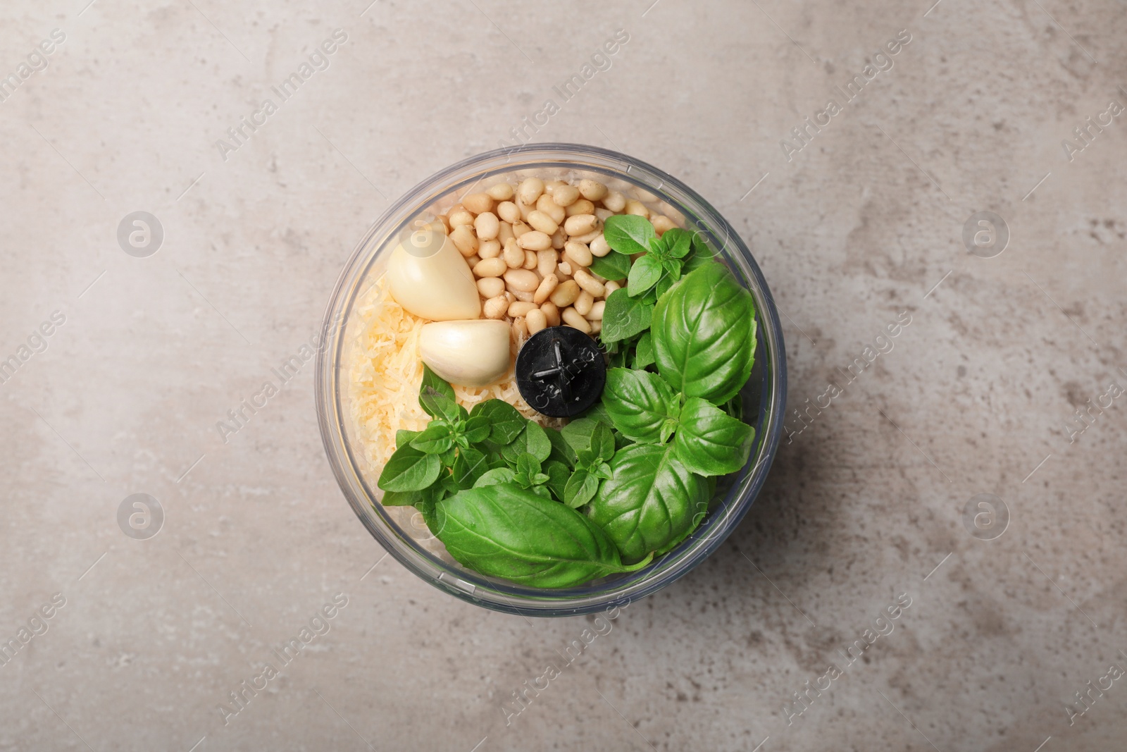 Photo of Ingredients for homemade basil pesto sauce in blender container on table, top view