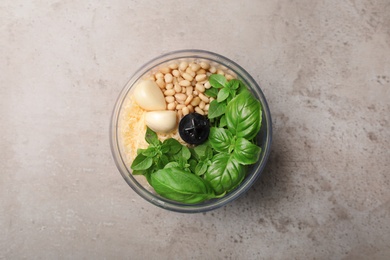 Photo of Ingredients for homemade basil pesto sauce in blender container on table, top view