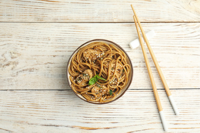 Tasty buckwheat noodles with meat on white wooden table, flat lay