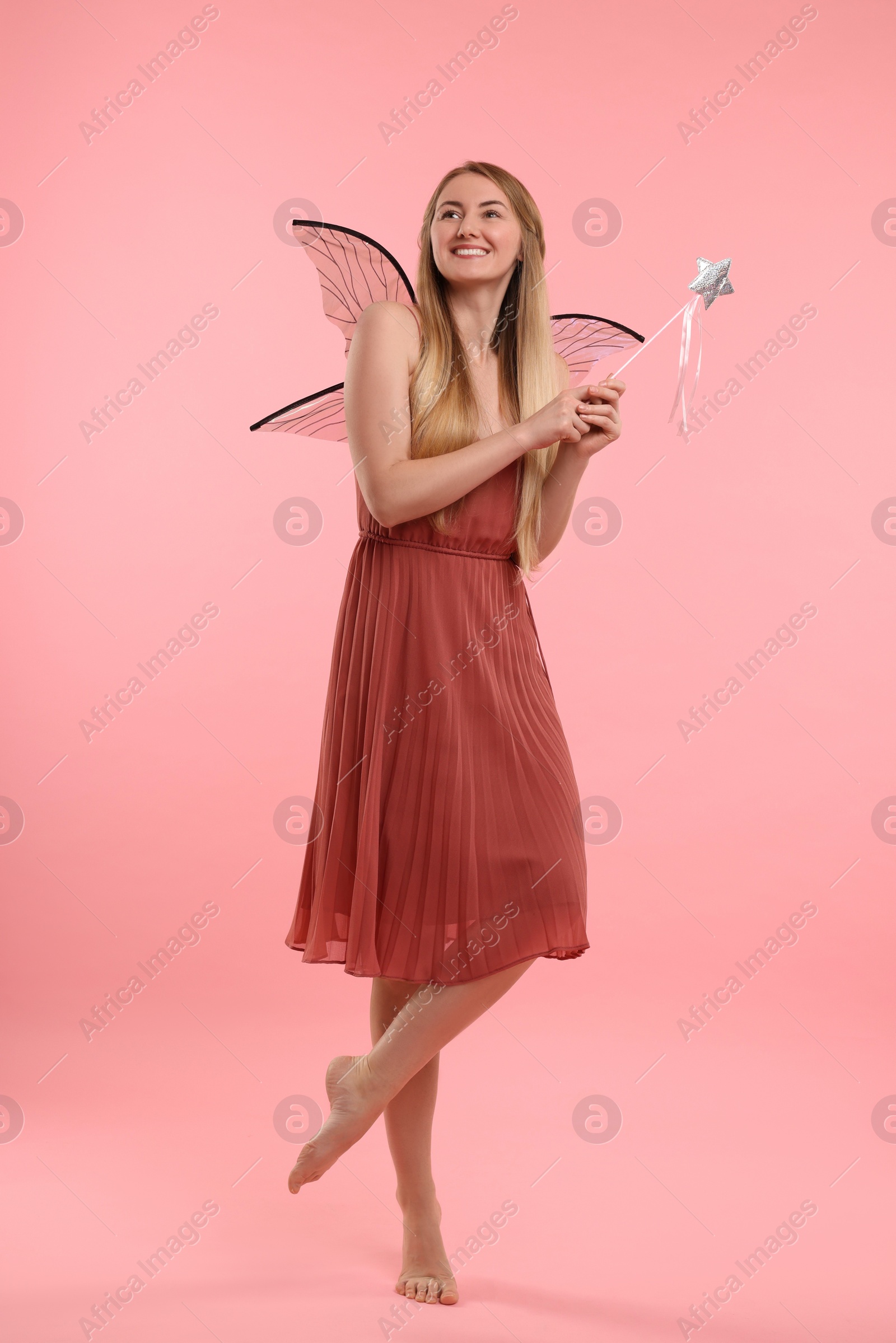 Photo of Beautiful girl in fairy costume with wings on pink background