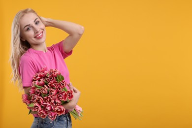 Happy young woman with beautiful bouquet on orange background. Space for text